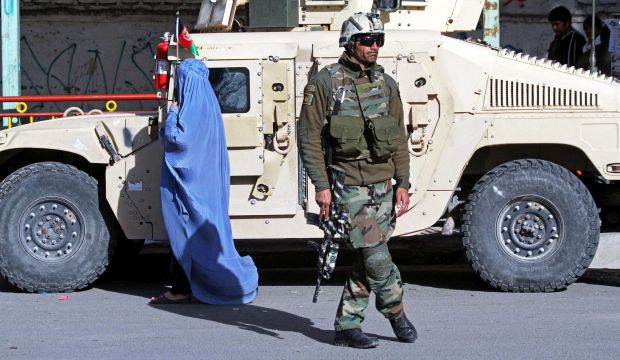 A burqa clad Afghan woman passes by Afghan security forces as they stand guard during in Herat, Afghanistan, 27 December 2014. (EPA/Jalil Rezayee)
