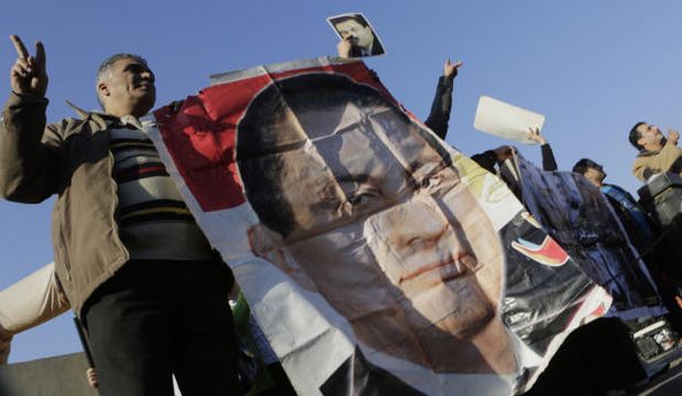 Supporters of former Egyptian president Hosni Mubarak wave by his poster as he was taken by a helicopter ambulance from Maadi Military Hospital to a court in Cairo, Egypt, on Saturday, November 29, 2014. (AP Photo/Amr Nabil)