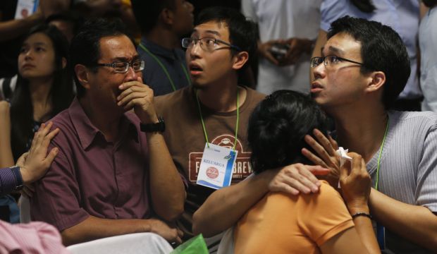 Family members of passengers onboard missing AirAsia flight QZ8501 react to the news that bodies and debris were found off the coast of Borneo island, while they wait at the airport in Surabaya, Indonesia, on December 30, 2014. (Reuters/Beawiharta) 