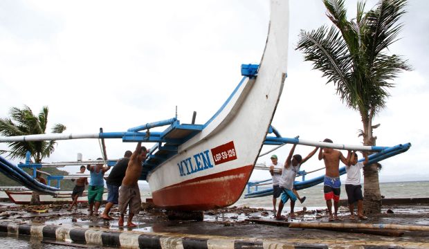 Fishermen carry their outrigger to higher ground in Legazpi City, Philippines, on December 5, 2014. (AFP Photo/Charism Sayat)