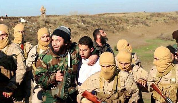 This image posted by the Raqqa Media Center, which monitors events in territory controlled by Islamic State militants with the permission of the extremist group, shows militants with a captured pilot, center, wearing a white shirt in Raqqa, Syria, Wednesday, Dec. 24, 2014. (AP Photo/Raqqa Media Center)