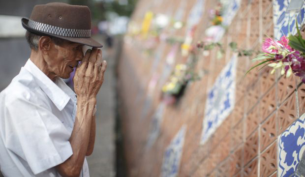 Somjit Bhuddharaj, 58, gestures after placing flowers next to a plaque with the name of his family, who was killed in the 2004 tsunami, at a wave-shaped memorial in Ban Nam Khem, a southern fishing village destroyed by the wave, December 26, 2014.  (Reuters/Athit Perawongmetha)