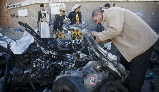 A police investigator collects evidence from wreckage at the scene of a car bomb outside a police academy in Sana'a, Yemen, on January 7, 2015. (AP Photo/Hani Mohammed)