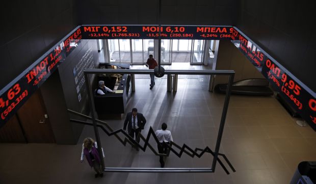 Employees of Athens Stock Exchange walk under screens showing falling stocks in red on January 28, 2015. (AP Photo/Petros Giannakouris)