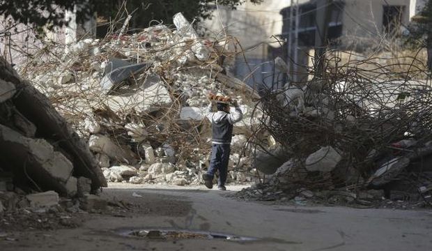 A boy selling sweets walks amid the damage of a collapsed buildings in Douma. (Reuters)