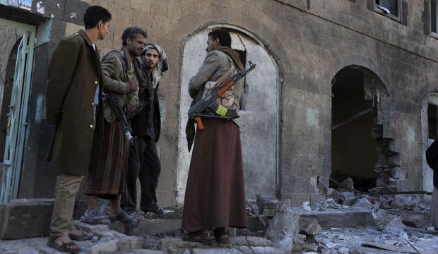 Survivors of the Shi'ite Houthi milita stand next to a hole in the wall left by a bomb blast targeting their base in Sana'a, Yemen, on January 5, 2015. (EPA/Yahya Arhab)