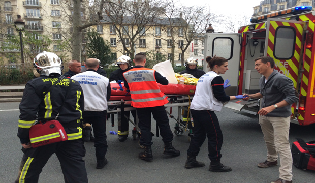 Firefighters carry an injured man on a stretcher in front of the offices of the French satirical newspaper Charlie Hebdo in Paris on January 7, 2015, after armed gunmen stormed the offices leaving at least 11 dead. (AFP Photo/Philippe Dupeyrat)
