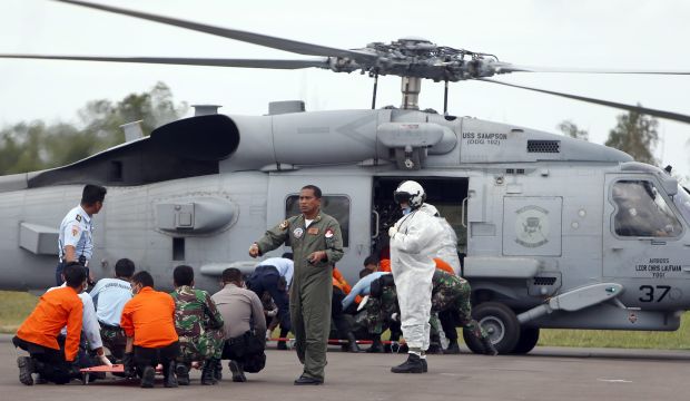 Indonesian rescuers and US Navy members unload bodies from a Seahawk helicopter at Iskandar Military Airport in Pangkalan Bun, Central Borneo, Indonesia, on January 2, 2015. (EPA/Adi Weda)
