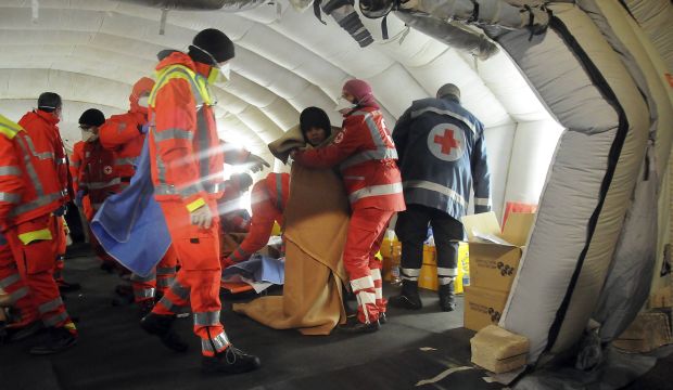 Emergency personnel help migrants who arrived in Italy onboard another ship that was rescued by the Italian Coast Guard on December 31, 2014. (Reuters/Stringer)