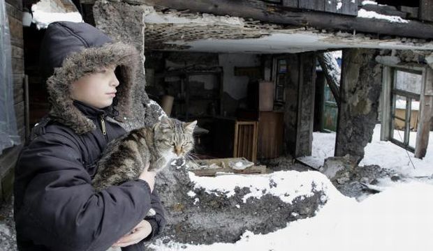 A local boy holds a cat outside of his home which reportedly was damaged by shelling, in Donetsk, Ukraine, 12 January 2014. (EPA photos)