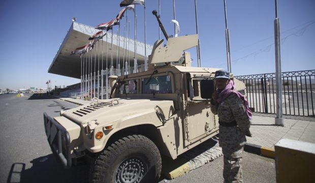 A Houthi fighter in army uniform stands to the door of a military vehicle which was seized from the army during recent clashes, outside an entrance to the presidential palace in Sana;a, on February 8, 2015.  (REUTERS/Mohamed al-Sayaghi)