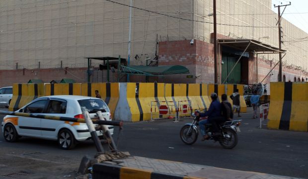 Yemenis drive past the exterior of Saudi Arabia's embassy complex in Sana'a after it closed following security concerns, on February 14, 2015. (AFP Photo/Mohammed Huwais)