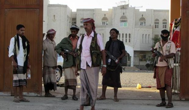 Armed men stand guard outside a local authority compound after taking it over in Yemen's southern port city of Aden, on February 16, 2015. (Reuters/Yaser Hasan)