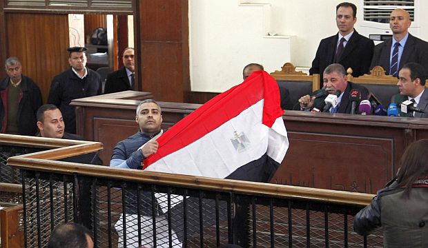 Al-Jazeera journalist Mohamed Fahmy raises an Egyptian national flag while talking to the judge during his retrial at a court in Cairo, on February 12, 2015. (Reuters/Asmaa Waguih)
