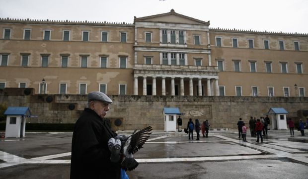 A man feeds pigeons in front of the parliament building in Athens, on February 23, 2015. (Reuters/Alkis Konstantinidis)