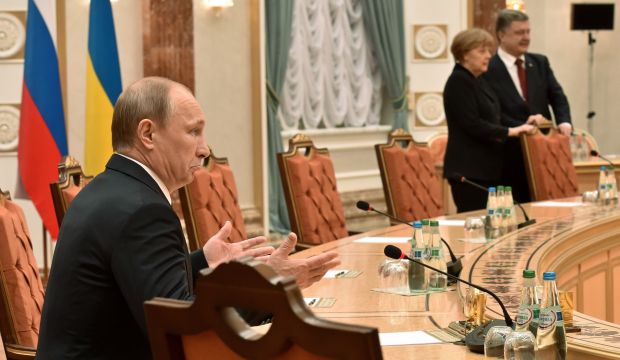 Russian President Vladimir Putin (L) gestures as German Chancellor Angela Merkel and Ukrainian President Petro Poroshenko stand nearby during peace talks in Minsk, Belarus, on February 11, 2015. (AP Photo/Kirill Kudryavtsev, Pool)
