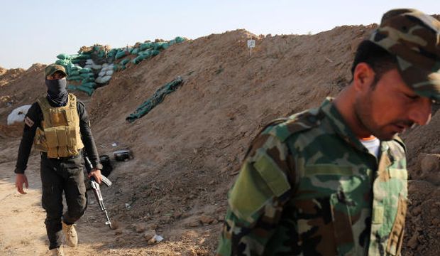 Shi’ite militia fighters walk along the frontline just outside Kirkuk, Iraq, on February 15, 2015. (AP Photo/Bram Janssen)