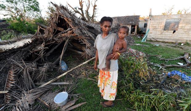 Lana Silona prepares food with her son Costello in front of their ruined home on the island of Tanna, Vanuatu, on March 17, 2015. (EPA/Dave Hunt)
