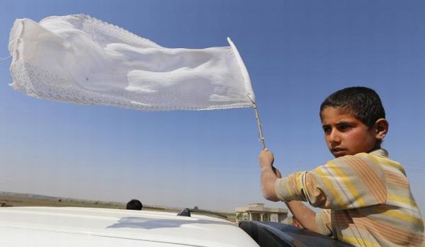 A boy displays a white flag as he passes through a checkpoint manned by Sunni fighters who have joined Shi'ite militia groups known collectively as the Popular Mobilization forces, in Salah Al-Din province, Iraq, on March 15, 2015. (Reuters)