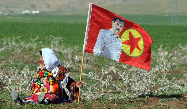 A Turkish Kurdish woman with a child sits next to a Kurdistan Workers' Party flag with a picture of the imprisoned Kurdish rebel leader Abdullah Ocalan in Silopi, Turkey, on March 2, 2015. (Reuters/Kadir Baris)