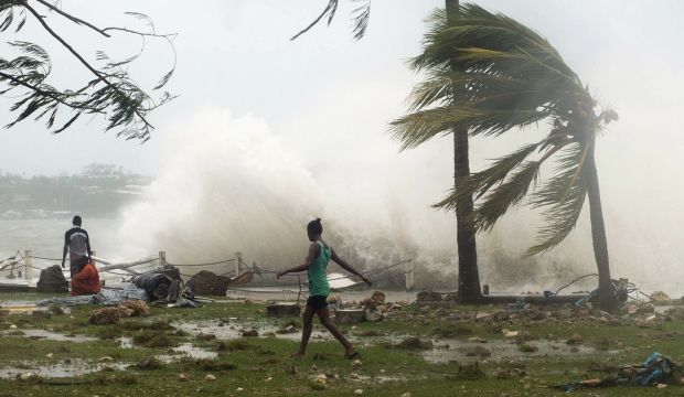 Local residents walk past debris as a wave breaks nearby in Port Vila, the capital city of the Pacific island nation of Vanuatu on March 14, 2015. (Reuters/Unicef Pacific)