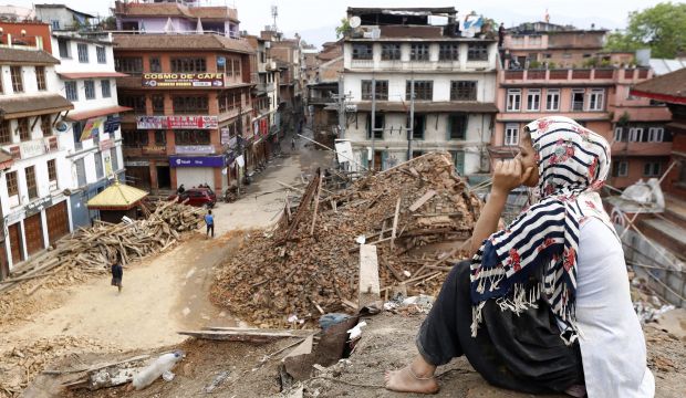 Sangita, a shop-owner, sits on top of a damaged temple as she watches rescue workers operating, in Kathmandu, Nepal, on April 29, 2015. (EPA/Abir Abdullah)