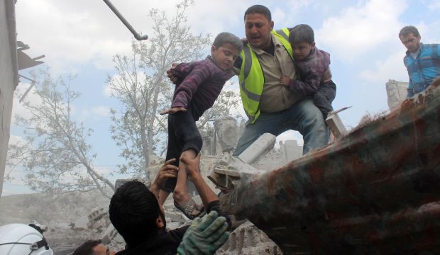 Syrian Civil Defense workers evacuate children from a building following a reported airstrike by government forces in a rebel-held neighborhood in Aleppo on April 14, 2015. (AFP Photo/Karam Al-Masri)