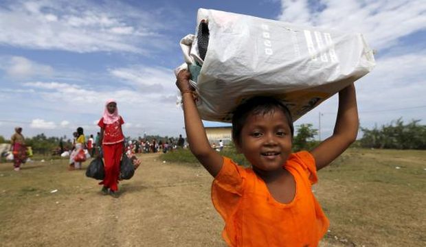 A Rohingya migrant child, who arrived in Indonesia by boat, carries belongings while walking to a bigger shelter inside a temporary compound for refugees in Kuala Cangkoi village in Lhoksukon, Indonesia's Aceh Province, on May 18, 2015. (Reuters/Beawiharta)
