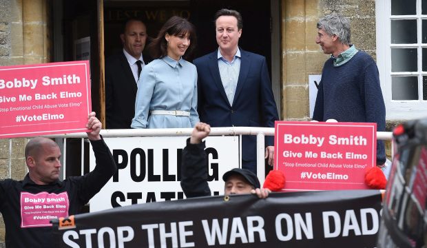 epa04736406 British Prime Minister and Conservative leader David Cameron (C-R) looks at 'Fathers For Justice' protesters as he exits a polling station after voting with his wife Samantha (C-L), at the village of Spelsbury in Oxfordshire, Britain, 07 May 2015. (EPA/Andy Rain)