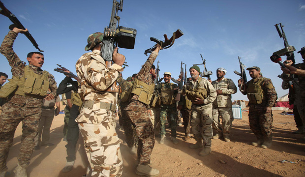 Iraqi fighters from the Shi'ite Muslim Al-Abbas popular mobilization unit hold up their weapons in the area surrounding the village of Nukhayb in the embattled Anbar province west of the capital Baghdad, on May 19, 2015. (AFP/Mohammed Sawaf)