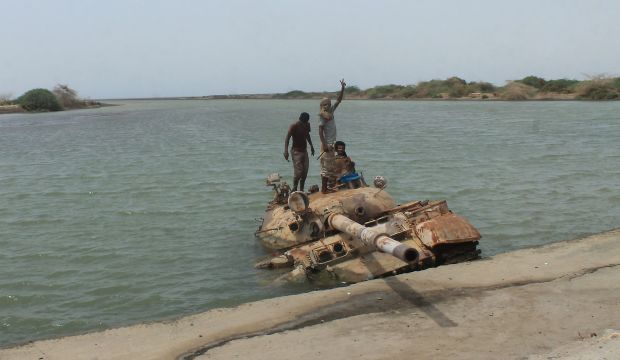 Yemeni pro-government forces, loyal to exiled President Abd Rabbuh Mansur Hadi, stand on a drowning tank they said belonged to Shi'ite Houthi fighters on the road to the town of Shaqra, in Abyan province on August 11, 2015.  (AFP PHOTO / SALEH AL-OBEIDI)