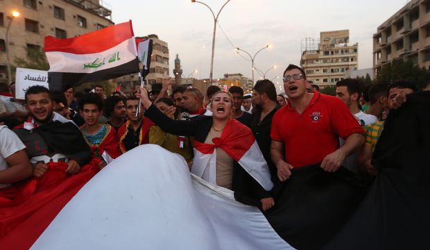 Protesters chant slogans in support of Iraqi Prime Minister Haider Al-Abadi as they carry a large national flag during a rally in Tahrir Square in Baghdad, Iraq, on Friday, Aug. 28, 2015. (AP Photo/Khalid Mohammed)