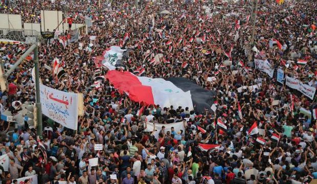 Protesters chant anti-government slogans as they carry a large national flag in a main square in Baghdad, Iraq, on August 7, 2015. (AP Photo/Karim Kadim)