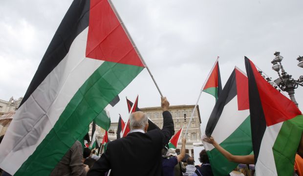 In this August 3, 2014 file photo, activists wave Palestinian flags as Pope Francis celebrates the Angelus noon prayer from his studio window overlooking St. Peter's square at the Vatican. (AP Photo/Riccardo De Luca)