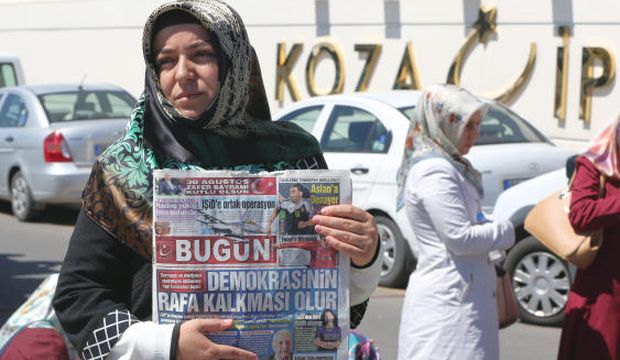 A woman holds a copy of the Bugün newspaper with the headline "Operation against the media is the end of democracy" while police search the premises of the newspaper's parent company Koza İpek Holding, in Ankara, Turkey, on September 1, 2015. (AP Photo/Burhan Ozbilici)