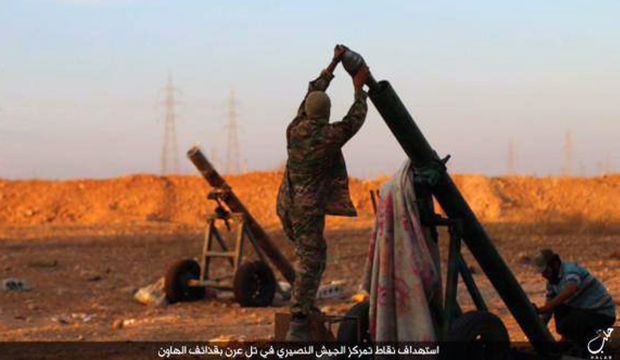 In this image posted on Thursday, October 8, 2015, by the Rased News Network, a Facebook page affiliated with Islamic State of Iraq and Syria (ISIS), shows ISIS militants preparing to fire a mortar to shell towards Syrian government forces positions at Tal Arn in Aleppo province, Syria.  (ISIS militant website via AP)