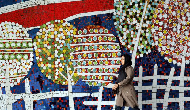 An Iranian woman walks past a mural on a street in the northwest of the capital Tehran, on October 19, 2015. (AFP PHOTO / ATTA KENARE)
