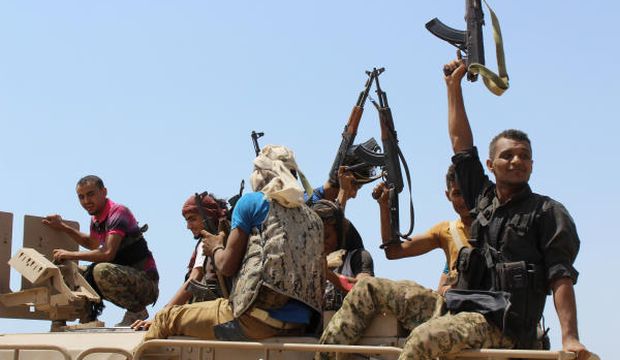 Fighters loyal to the Yemeni government hold up their weapons as they ride on an armored vehicle near the strait of Bab El-Mandab, west of the southern port city of Aden, Yemen, to take back control of the strait, on October 2, 2015. (AP Photo/Wael Qubady)