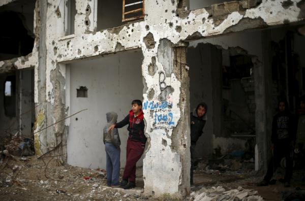 Palestinians take cover in a building that was damaged during the 2014 war, on a rainy day in Beit Hanoun in the northern Gaza Strip (Reuters)
