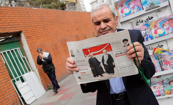 An Iranian man holds a copy of the daily 'Shargh' newspaper with pictures of Iranian President Hassan Rouhani and former president Akbar Hashemi Rafsanjani on it. The headline reads 'Decisive victory for the reformist' (EPA)