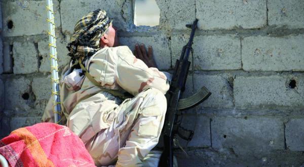 Iraqi Solidier peaking through a hole in a wall in Fallujah -Iraq- Reuters