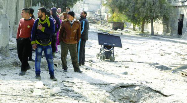 Syrians standing near a pit that was caused by Syrian rigeme airforce attack on Aleppo