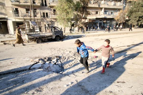 Boys run near a hole in the ground after airstrikes by pro-Syrian government forces in the rebel held al-Sakhour neighborhood of Aleppo (Reuters)