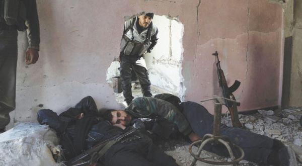 Fighters of Al-Rahman Corps rest inside a building on the frontline in the town of Bala in the eastern Ghouta region, on the outskirts of the capital Damascus (AFP)