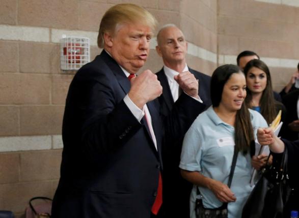 Republican U.S. presidential candidate Donald Trump flexes his muscles as he talks with caucus participants while visiting a Nevada Republican caucus site at Palo Verde High School in Las Vegas, Nevada February 23, 2016. REUTERS/Jim Young