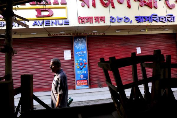 ndian commuters walk past a closed gold jewellery shop in Calcutta, eastern India