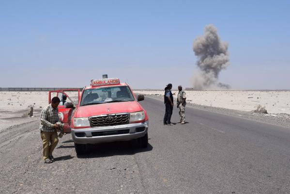 SUMMARY : Yemeni men stand in a street as smoke billows in the background after security forces neutralised unexploded ordnance confiscated from the Shiite Huthi rebels and militant extremists, in the desert of al-Alam, east of the southern Yemeni port city of Aden, on March 10, 2016.- / AFP PHOTO / SALEH AL-OBEIDI