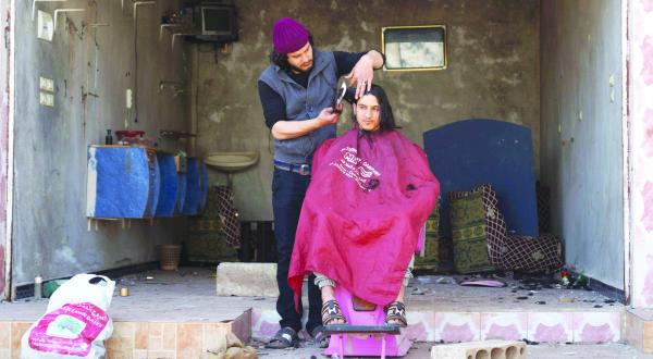 A Syrian has his hair shaved in a salon that sustained damage in the town of Al-Ghariya that is under Syrian opposition control in the governorate of Daraa yesterday (Reuters)