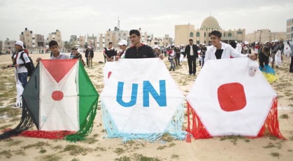 Palestinian children wave the Palestinian, Japanese and UN flags at an event in Khan Younis, Gaza Strip yesterday (AFP)
